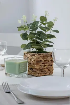 a table with a candle and a plant in a basket at Modern Apartment with Parking near Tauron Arena by Rent like home in Kraków