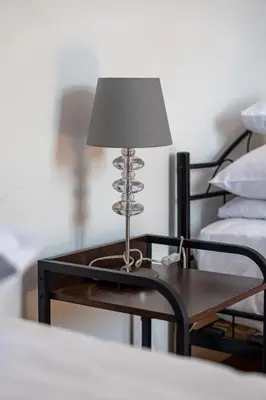a table with a lamp on it next to a bed at Vista View Apartment in Kraków