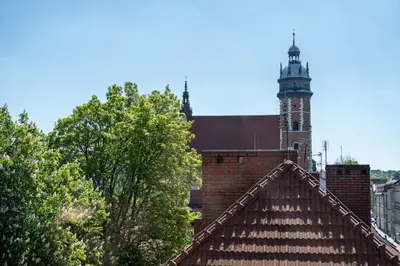 a clock tower on top of a brick building with trees at Vista View Apartment in Kraków