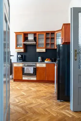a kitchen with wooden cabinets and a black refrigerator at Vista View Apartment in Kraków