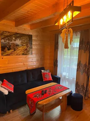 a living room with a black couch and a table at Leśne Zacisze in Ochotnica Górna
