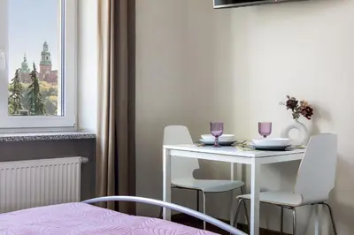 a white table and chairs in a room with a window at Wavelo Apartments in Kraków