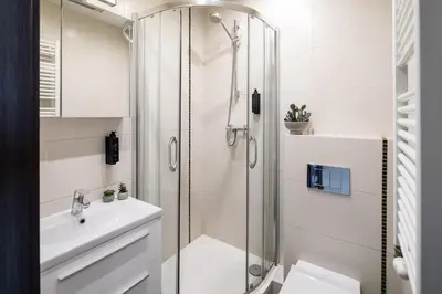a white bathroom with a shower and a sink at Wavelo Apartments in Kraków