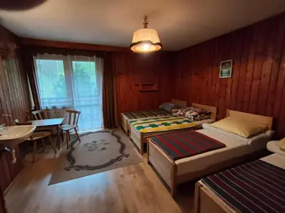 a bedroom with two beds and a table and a dining room at Chata Pod Kwiatkiem in Zawoja