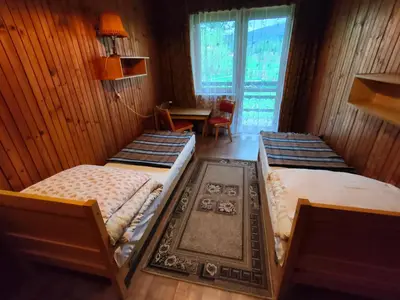 a room with three beds and a table and a window at Chata Pod Kwiatkiem in Zawoja