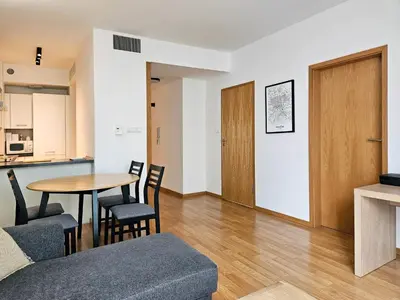 a living room with a table and chairs and a kitchen at Old Town Plaza Apartment in Kraków