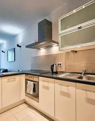 a kitchen with white cabinets and a sink at Old Town Plaza Apartment in Kraków