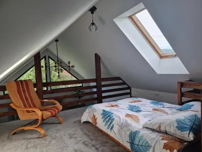 a bedroom with a bed and a chair in a attic at Domek przy drodze in Chyszówki