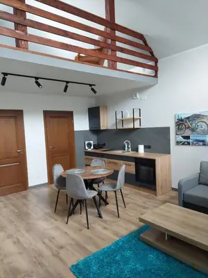 a living room with a table and chairs and a kitchen at Domek przy drodze in Chyszówki