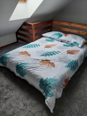 a bed with a blanket with leaves on it at Domek przy drodze in Chyszówki