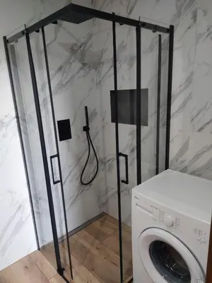 a shower in a bathroom with a washing machine at Domek przy drodze in Chyszówki
