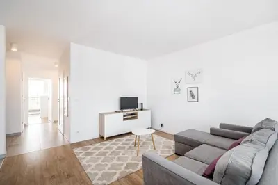 a white living room with a couch and a tv at Tauron Arena Residence WAWELOFTS in Kraków