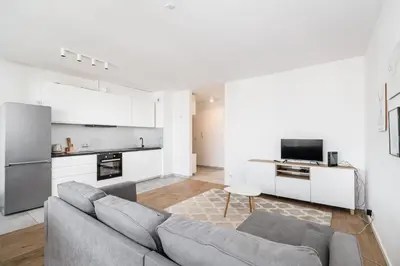 a living room with a couch and a kitchen at Tauron Arena Residence WAWELOFTS in Kraków