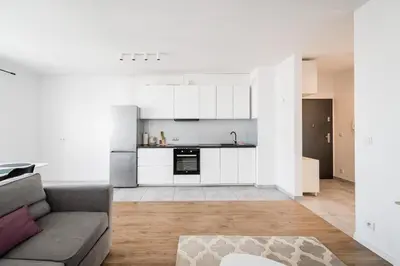 a living room with a couch and a kitchen at Tauron Arena Residence WAWELOFTS in Kraków
