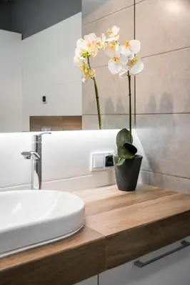 a bathroom with a sink and a vase with flowers on a counter at Tauron Arena Residence WAWELOFTS in Kraków