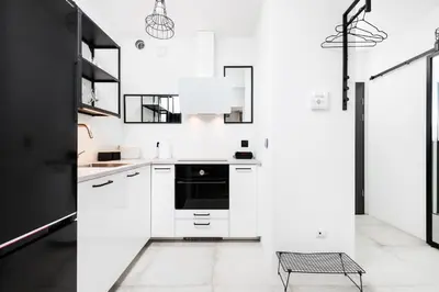 a kitchen with white cabinets and a black refrigerator at Kraków Kazimierz Charm - by Upstairs in Kraków
