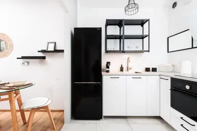 a kitchen with white cabinets and a black refrigerator at Kraków Kazimierz Charm - by Upstairs in Kraków