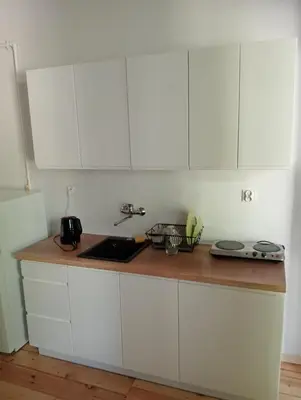 a kitchen with white cabinets and a wooden counter top at Apartament Central Station Batorego in Kraków