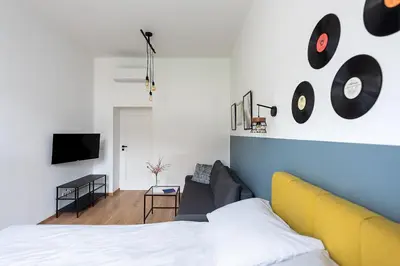 a bedroom with a bed and a couch and a tv at St Florian Apartments in Kraków