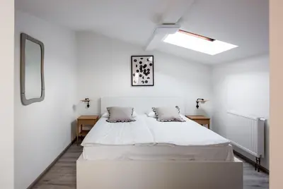 a white bedroom with a large white bed with two pillows at St Florian Apartments in Kraków