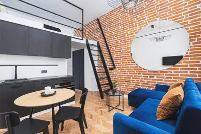 a living room with a blue couch and a brick wall at Main Station - Radziwiłłowska 27 in Kraków