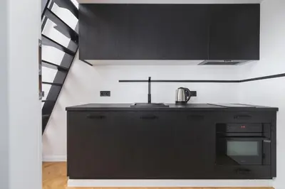 a kitchen with black cabinets and a black stove top oven at Studio apartment - Radziwiłłowska 27 in Kraków