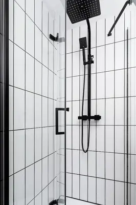 a shower in a bathroom with white tiled walls at Studio apartment - Radziwiłłowska 27 in Kraków