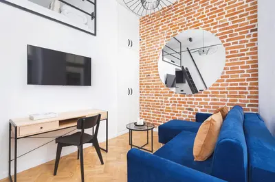 a living room with a blue couch and a brick wall at Studio apartment - Radziwiłłowska 27 in Kraków