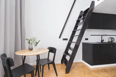 a dining room with a table and a spiral staircase at Studio apartment - Radziwiłłowska 27 in Kraków