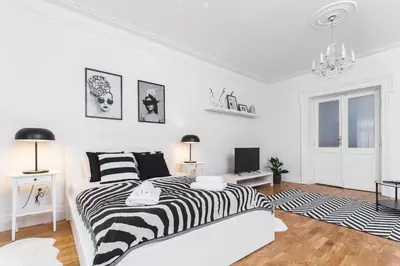 a bedroom with a black and white bed and a chandelier at Krakowska 16 Street Kazimierz District in Kraków