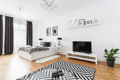a white living room with a bed and a flat screen tv at Krakowska 16 Street Kazimierz District in Kraków
