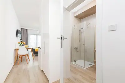 a white bathroom with a shower and a table at Studio with balcony - Rajska 3 Street in Kraków