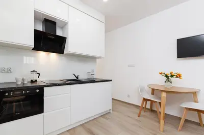 a kitchen with white cabinets and a wooden table at Studio with balcony - Rajska 3 Street in Kraków