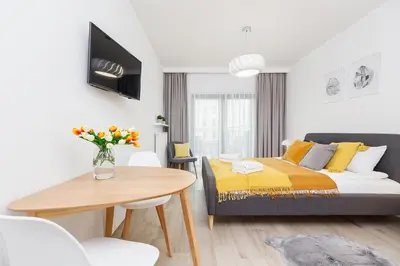 a bedroom with a bed and a table with a vase of flowers at Studio with balcony - Rajska 3 Street in Kraków