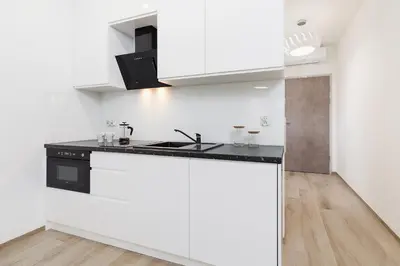 a kitchen with white cabinets and a black counter top at Studio with balcony - Rajska 3 Street in Kraków
