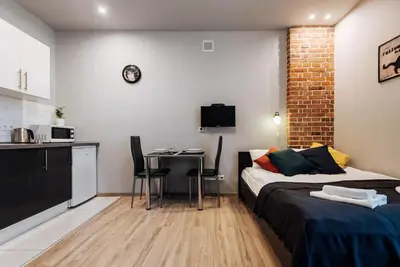a bedroom with a bed and a table and a kitchen at Studio with balcony - Rzeszowska 4 Street in Kraków