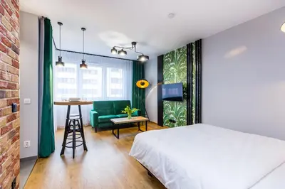 a bedroom with a bed and a table and a green chair at Premium Vintage Apartament by Krakow Home in Kraków