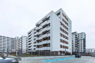 a white apartment building with cars parked in a parking lot at Premium Vintage Apartament by Krakow Home in Kraków