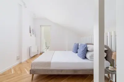 a white bedroom with a large bed with blue pillows at Apartment with balcony - Rejtana 10 in Kraków