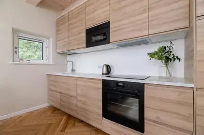 a kitchen with wooden cabinets and a black oven at Apartment with balcony - Rejtana 10 in Kraków