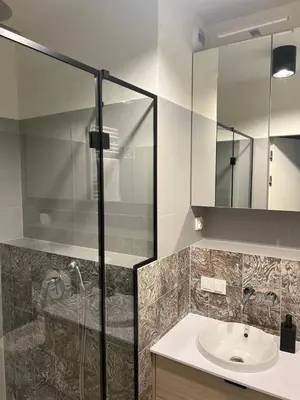 a bathroom with a sink and a glass shower at Tutu Kraków Comfort in Kraków