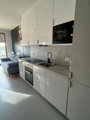 a kitchen with white cabinets and a sink and a couch at Tutu Kraków Comfort in Kraków
