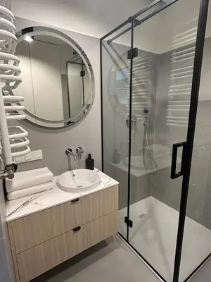 a bathroom with a sink and a shower with a mirror at Tutu Kraków Comfort in Kraków