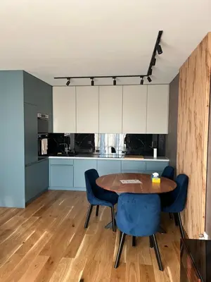 a kitchen with a wooden table and blue chairs at Tutu Kraków Comfort in Kraków