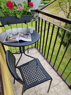 a table and chair on a balcony with a newspaper at Moje miejsce Zator in Zator