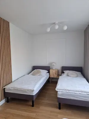 two beds in a room with white walls and wooden floors at Moje miejsce Zator in Zator