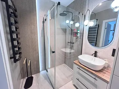 a bathroom with a sink and a shower with a mirror at ApartmentPrestige Soho in Kraków