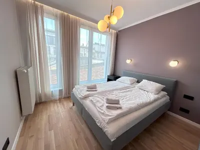 a bedroom with a bed with white sheets and windows at ApartmentPrestige Soho in Kraków