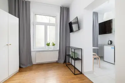 a white living room with a window and a table at Studio apartment with AC - Długa 65 in Kraków