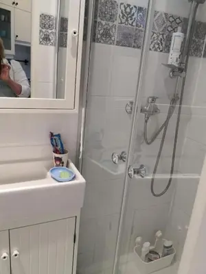 a bathroom with a shower and a person taking a picture at wawel hostel in Kraków
